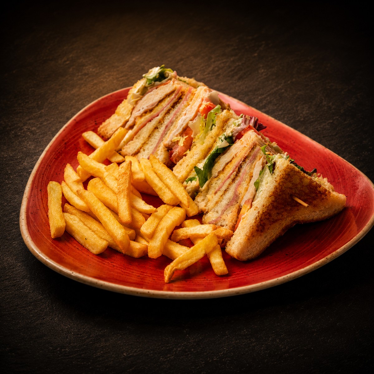 Sándwich Emalu Club cortado en triángulos con patatas fritas