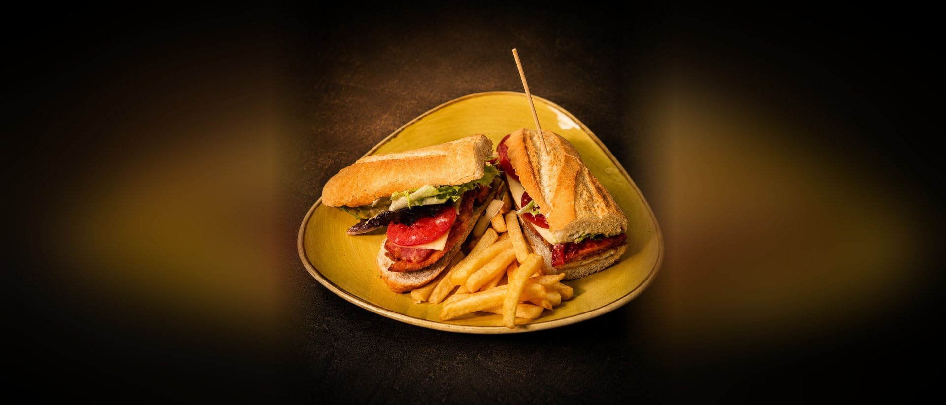 Bocadillo extremeño de lomo con queso y tomate, servido con patatas fritas