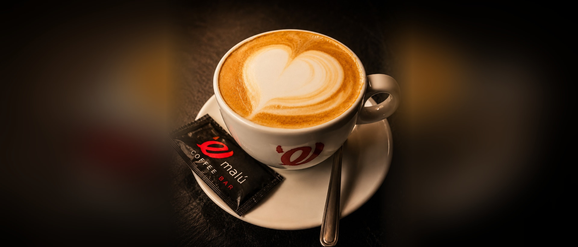 Café con leche con arte latte en taza de Emalú Coffee Bar